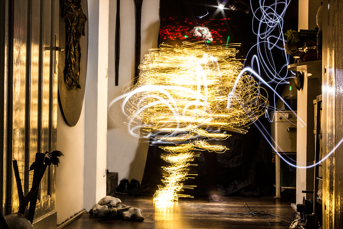 Fotografische Licht-Inszenierung, Einstellung 4. Eine Frau erstrahlt durch Lichtspuren, die durch Langzeitbelichtung die Körperbewegungen nachzeichnen. Die Frequenz der Bewegungen scheint weiter zuzunehmen.